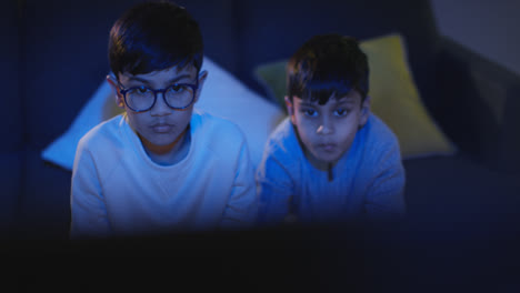 Front-View-Of-Two-Young-Boys-At-Home-Having-Fun-Playing-With-Computer-Games-Console-On-TV-Holding-Controllers-Late-At-Night